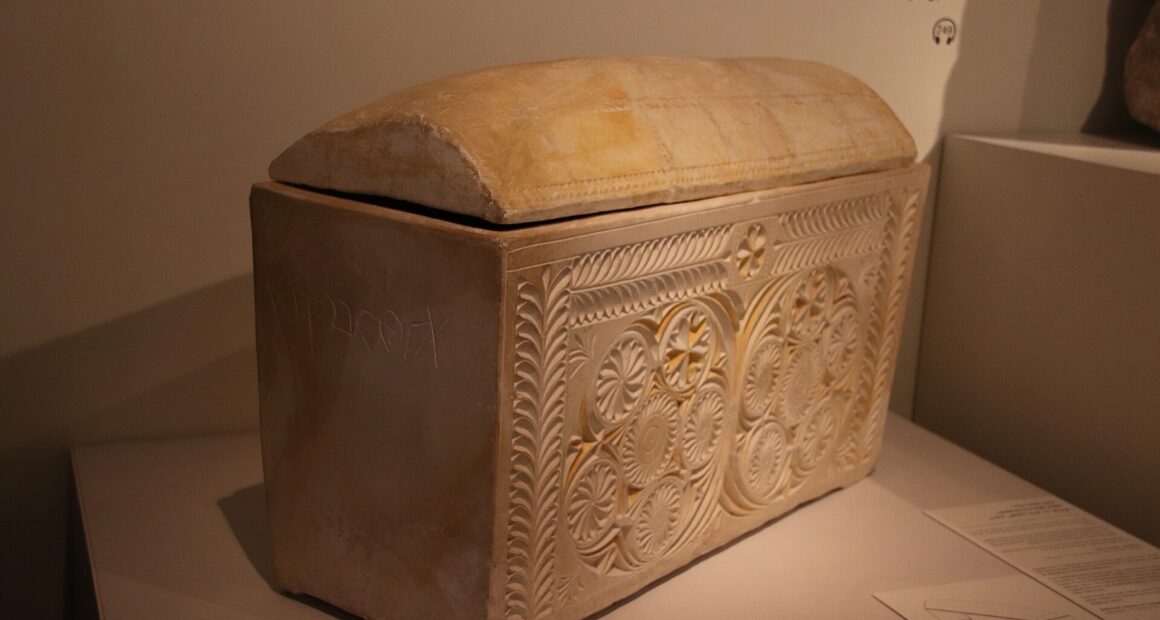Decorated limestone ossuary from first-century Jerusalem, carved with rosettes, in a museum case.