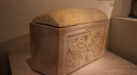Decorated limestone ossuary from first-century Jerusalem, carved with rosettes, in a museum case.